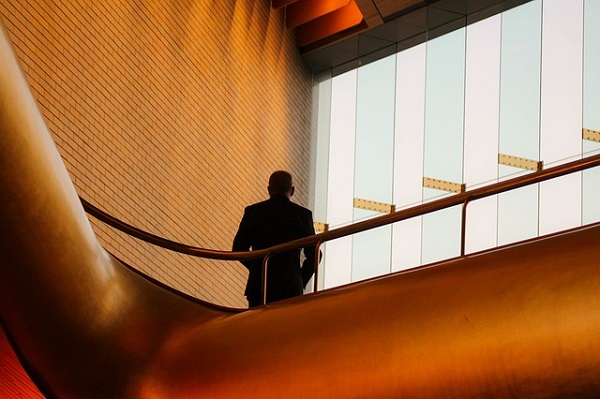 A business person standing on a copper coloured office balcony