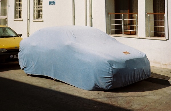 A parked car with a dust cover over the top