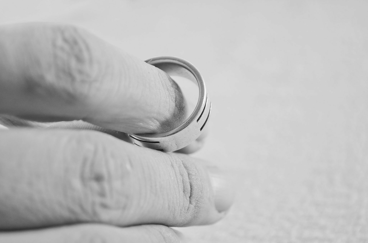 A hand holding a wedding ring