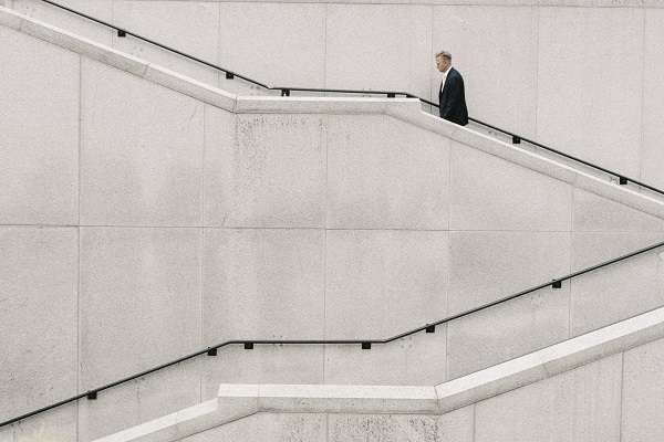 Business person walking up a flight of grey concrete stairs