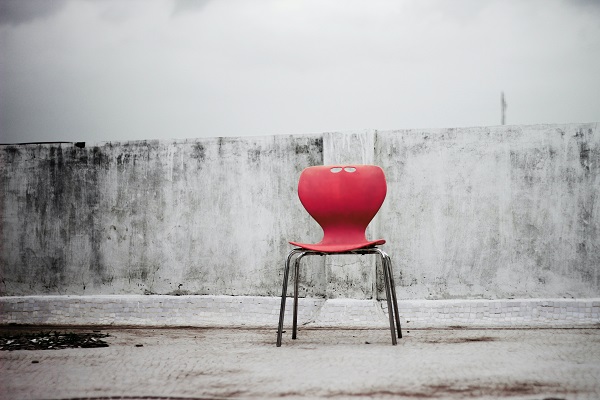 A red chair next to a dirty white wall