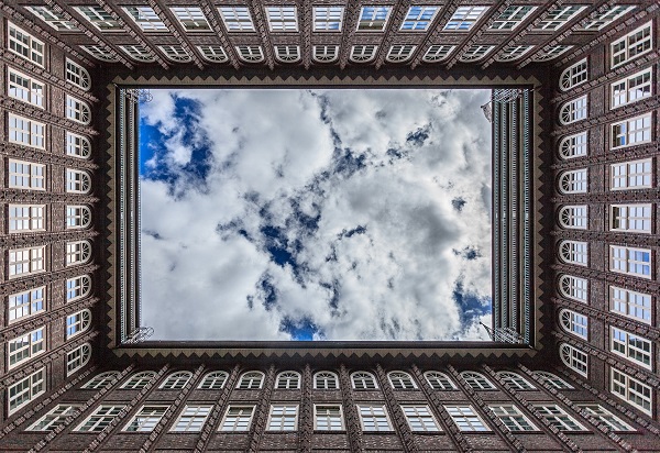 Looking up from the interior of an office courtyard to the sky above